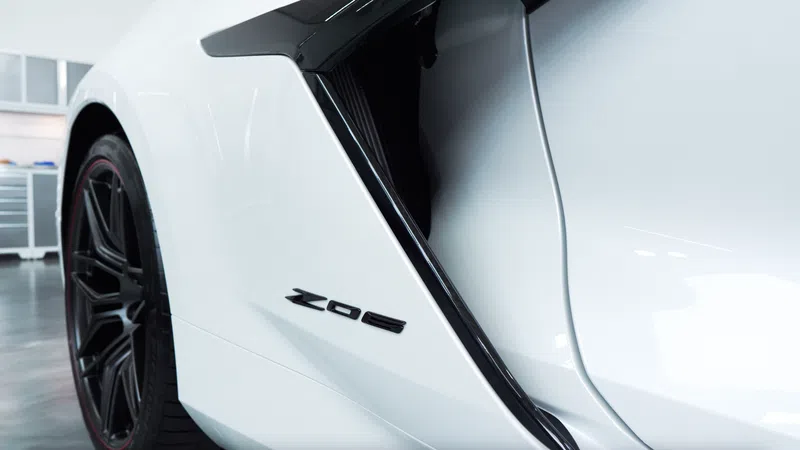 Close-up of a white sports car side panel with Z06 badge and black rear wheel in a garage setting.