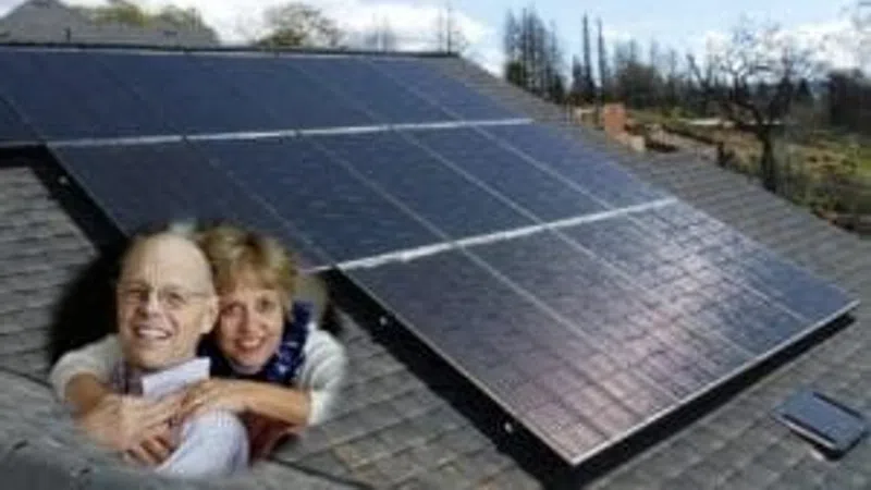 Smiling couple embracing on rooftop near large solar panels under blue sky with trees in background