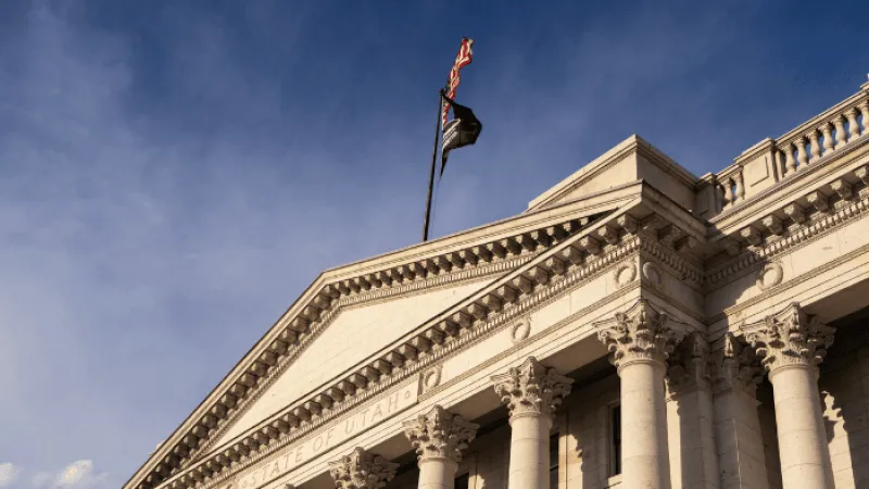 Classical-style government building in Utah with Corinthian columns and flags against a clear sky.