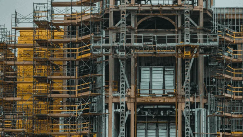 Detailed view of a building under construction with extensive yellow scaffolding and metal framework.