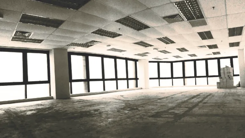 Empty spacious office interior with large windows and tiled ceiling ready for renovation or furnishing