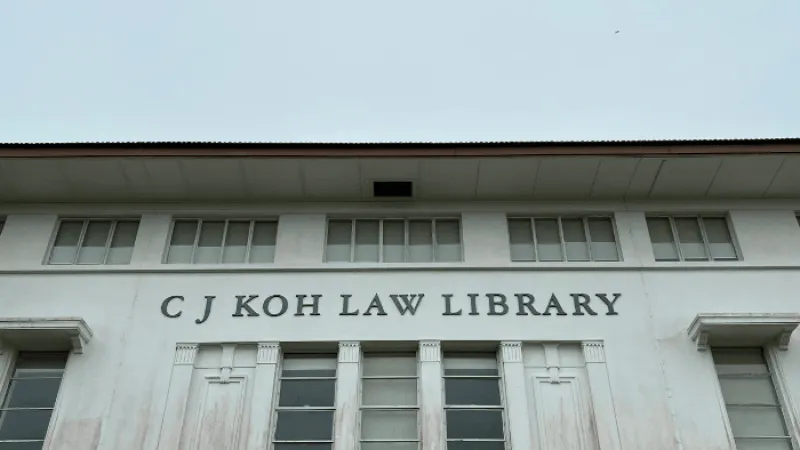 Facade of C J Koh Law Library with large windows and clear signage under a blue sky.