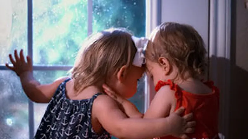 two girls kissing in front of a window