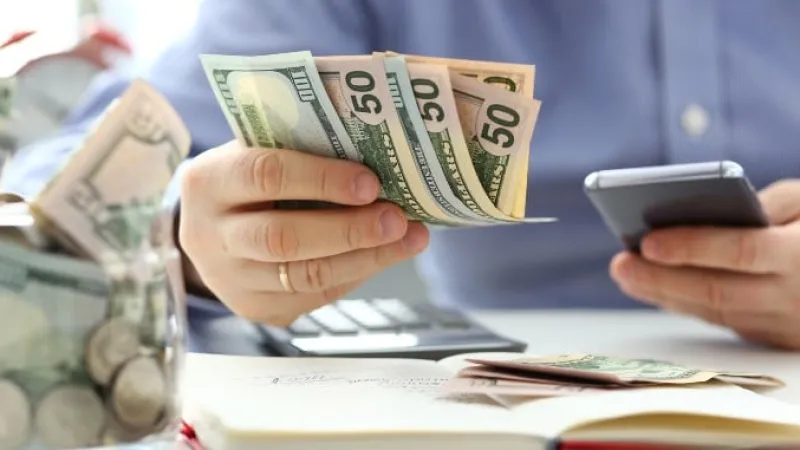 a person holding a phone and money