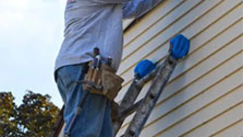 a man on a ladder painting a house