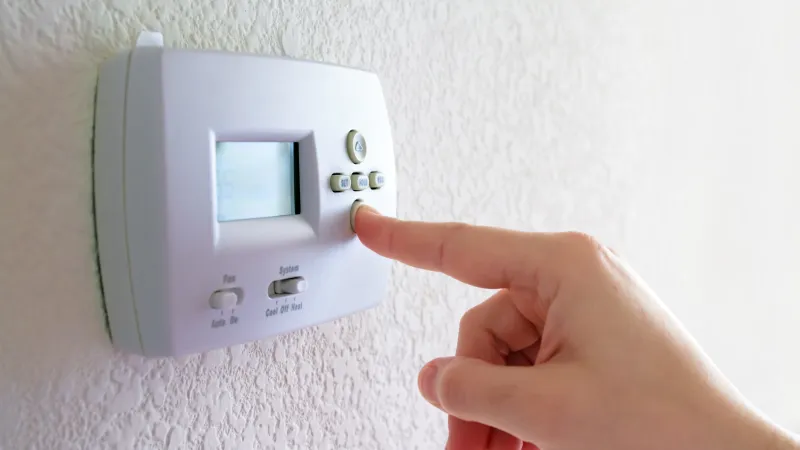 a hand holding operating a thermostat