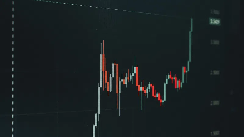 Close-up of a candlestick stock chart showing fluctuating prices with a sharp upward trend on a dark background.