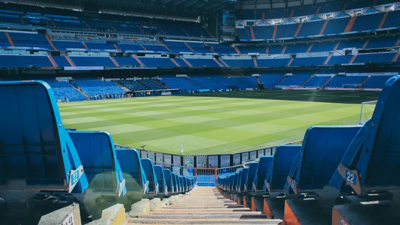 a sports stadium with blue seats with Santiago Bernabéu Stadium in the background