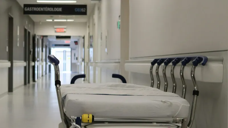 Empty hospital stretcher parked in a bright white corridor near gastroenterology department.