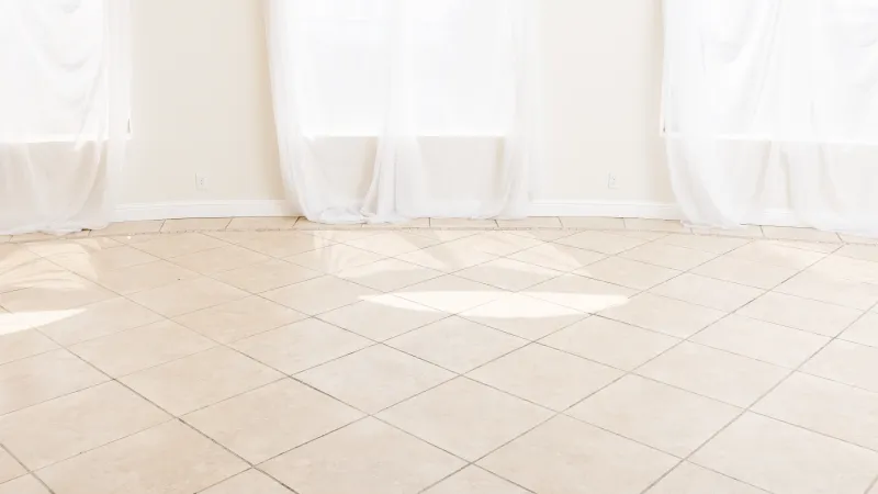 a tan tiled room with white thin curtains hanging in winter