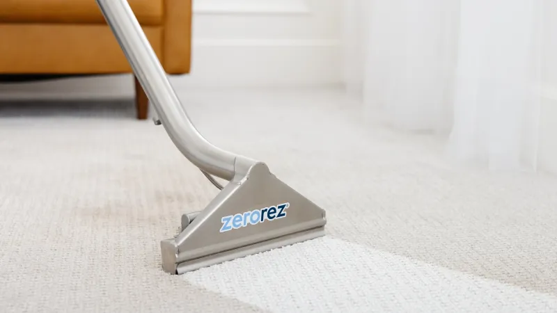 a close-up of Zerorez Zr Wand cleaning dirt on a light gray textured carpet to help eliminate dust mites from hot water extraction methods