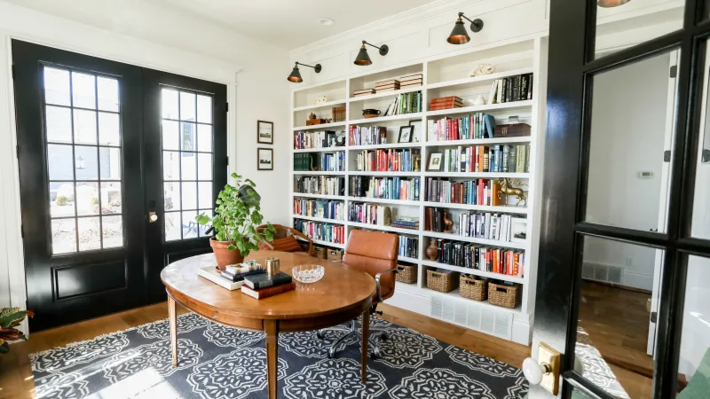 a room with a table and shelves with books on it