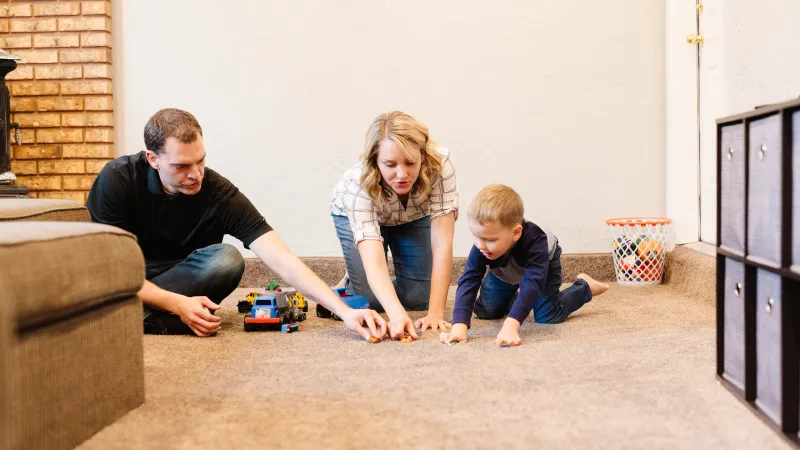 a man and woman playing with a baby on the floor