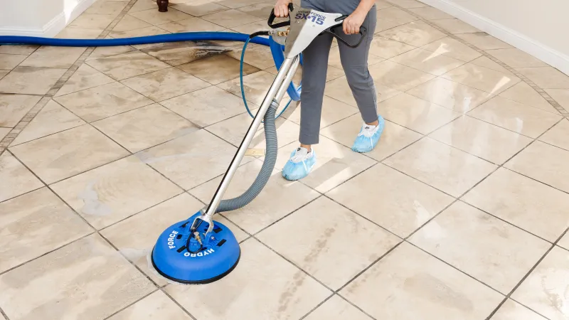 a Zerorez technician cleaning a tile floor with a hydro force steam cleaning wand
