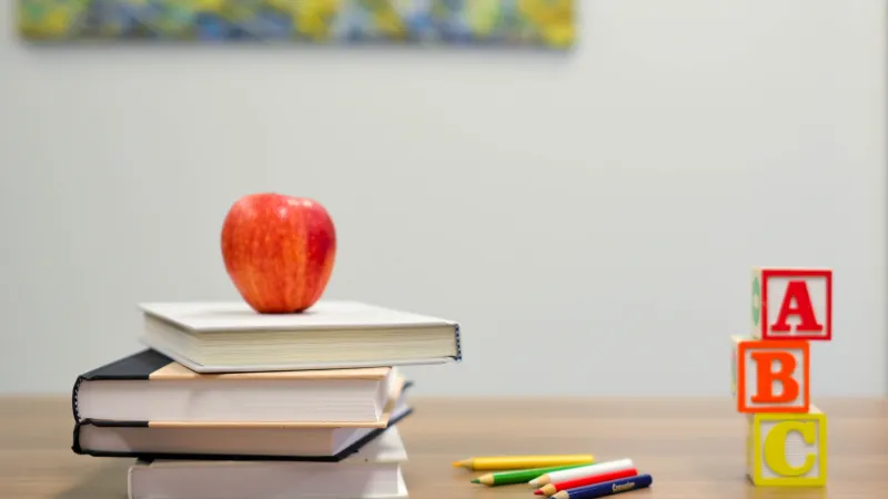 a red apple on top of a stack of books