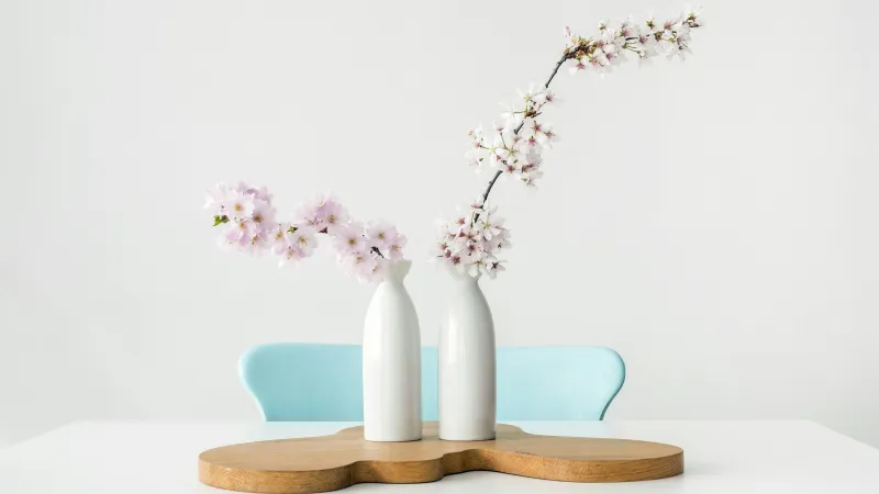 a couple of white vases with flowers in them