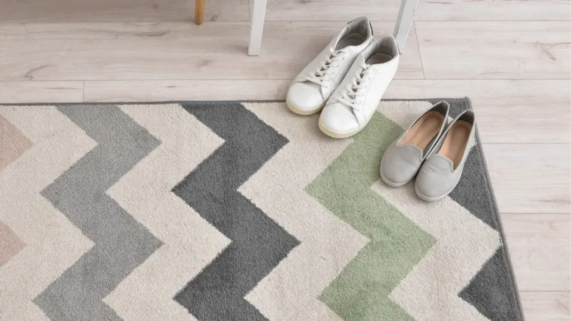 a pair of white shoes on a zig zag rug on light hardwood floors