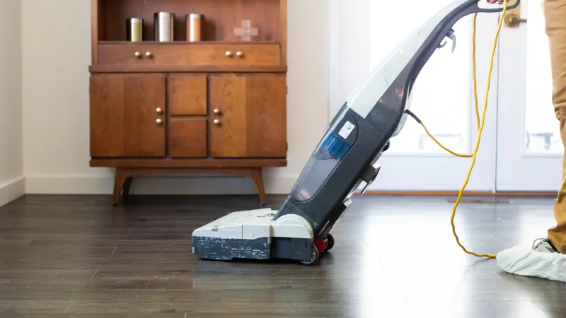 a person holding a vacuum cleaner on a hardwood floor