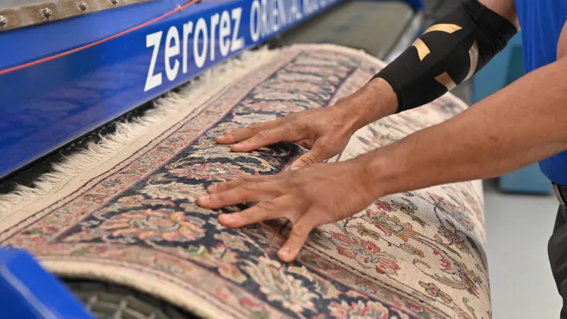 Close up a male Zerorez technician's hands on an oriental wool rug cleaning it with the Zerorez rug cleaning machine