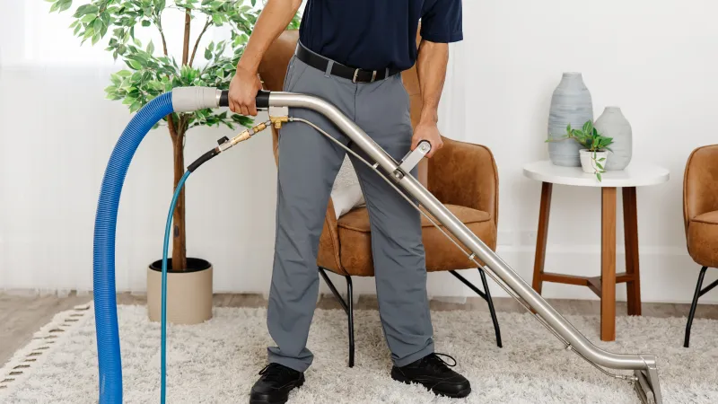 a man holding a cleaning wand standing on an area rug