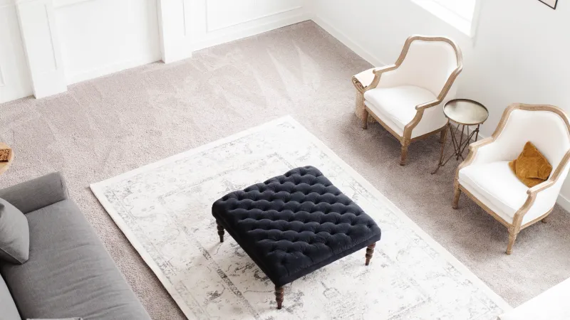 a living room with a couch and chairs with carpet and a rug