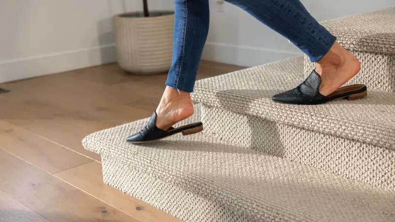 a person's feet in black sandals on a tile floor