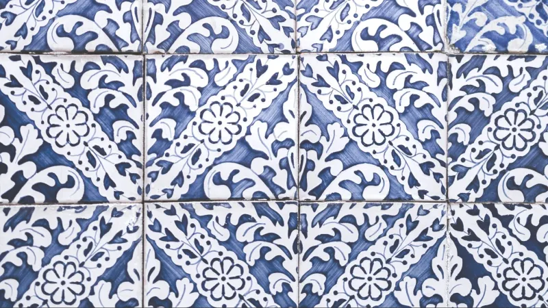 patterned blue and white tiles with cracking grout between them