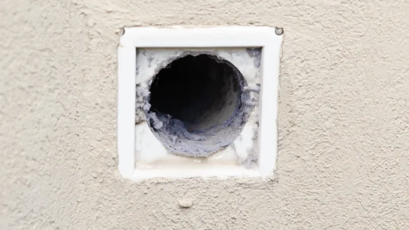 close up of the outside part of a dryer vent with lint inside of it