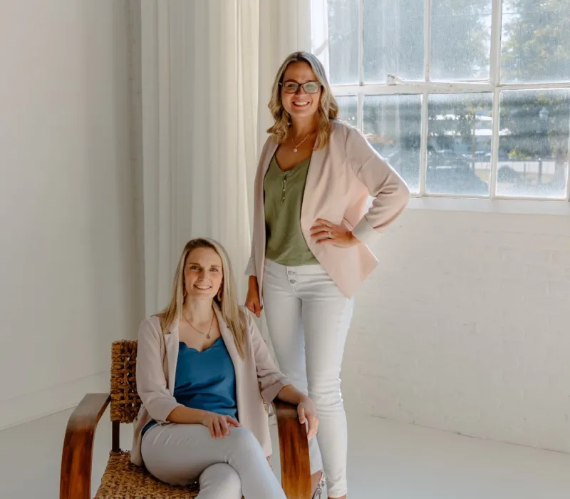 a woman sitting on a chair next to another woman