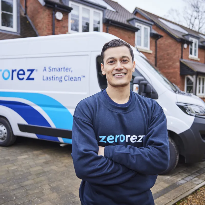 Smiling Zerorez technician in front of service van near suburban home, promoting cleaning services.