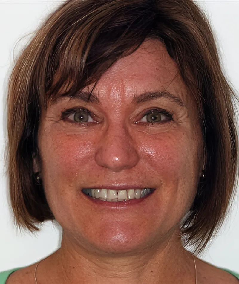 Close-up portrait of a smiling woman with short brown hair and green eyes wearing a green shirt.
