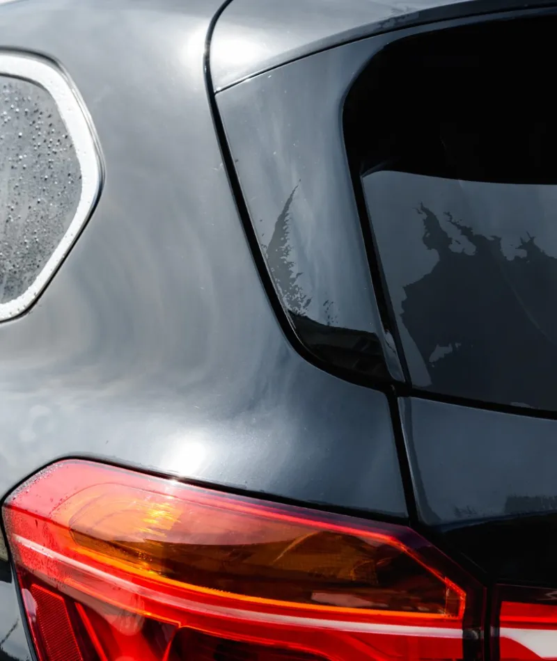 Comparison of dirty and clean black SUV rear windows and taillights under daylight outdoor conditions.