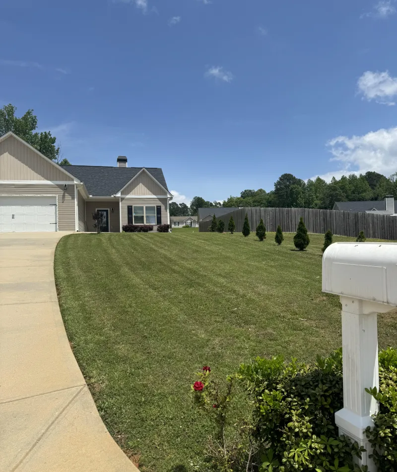 a yard with a fence and a house in the background