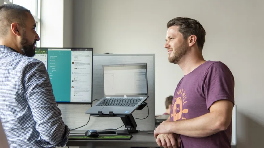 a couple of men looking at a laptop