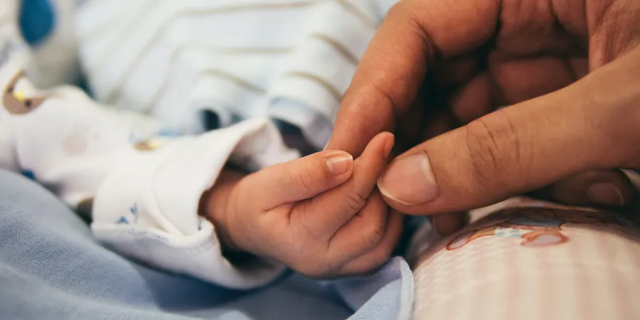 a hand holding a baby