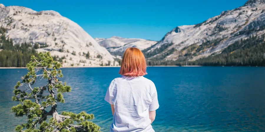a person standing in front of water and a mountain in the background
