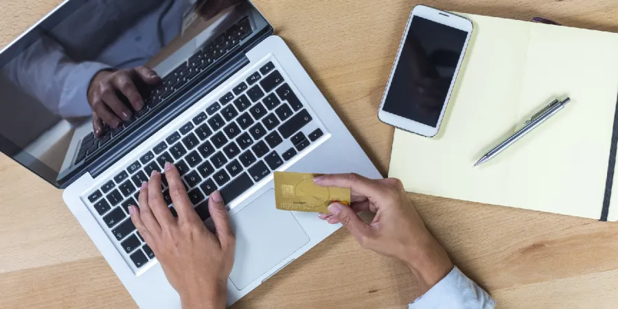 a person using a laptop holding a credit card