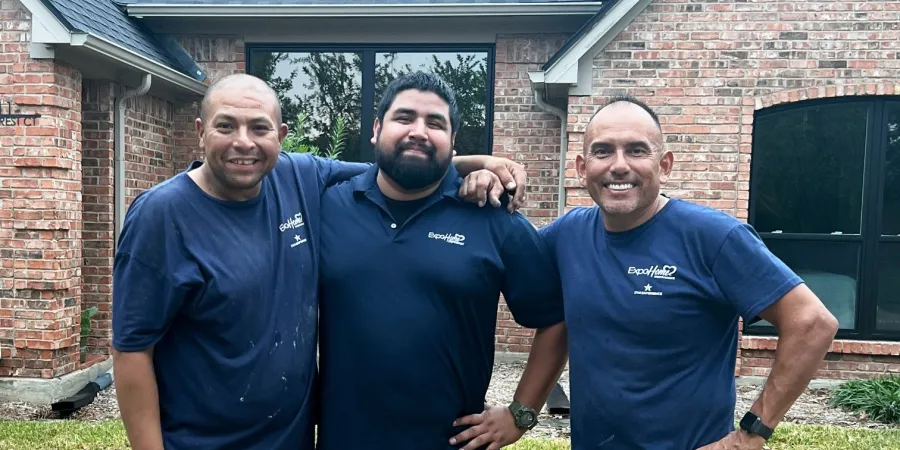 a group of men posing for a photo in front of a house