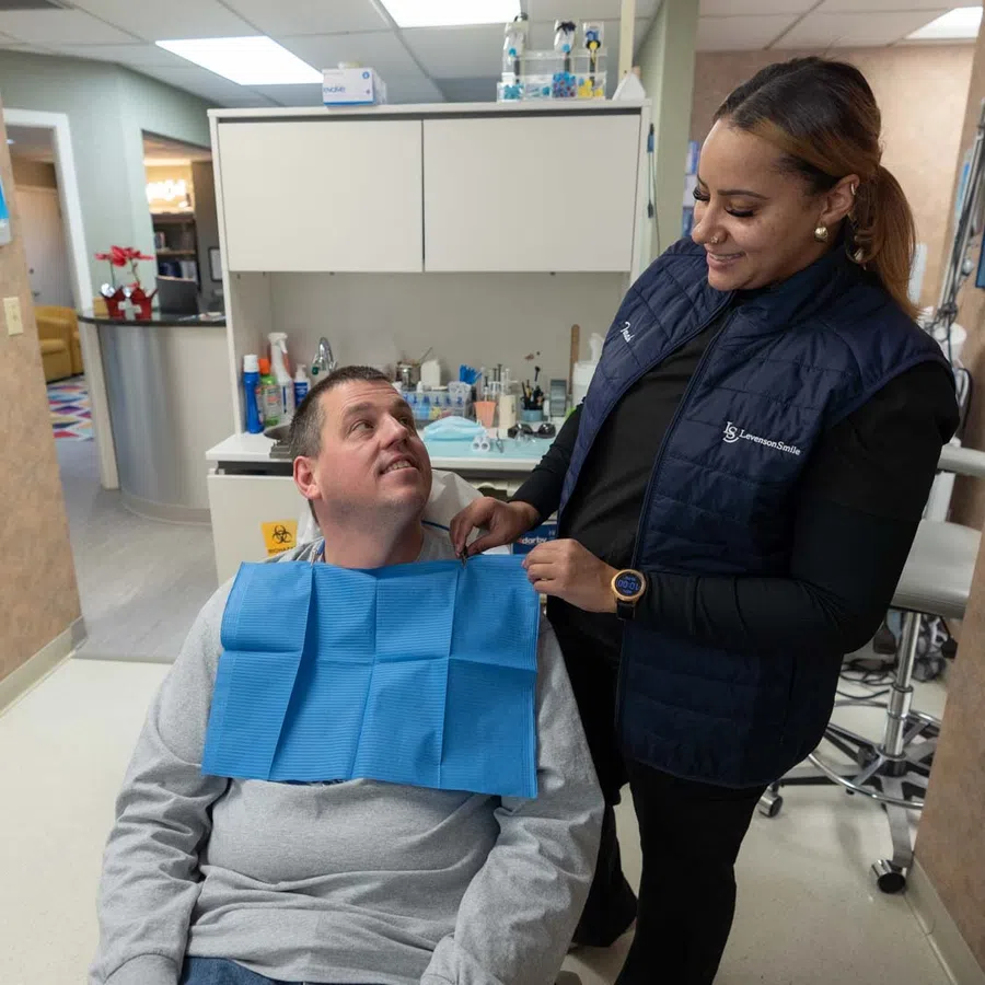 Dentist adjusts patient bib in a clean, modern dental clinic during a checkup appointment.