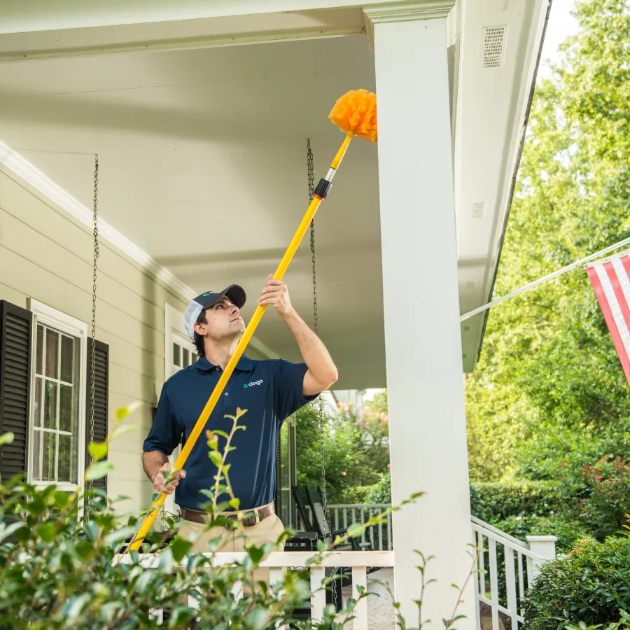 Cingo employee removing cobwebs from exterior of house