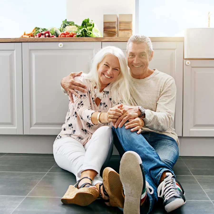 a man and woman sitting on a chair in a kitchen