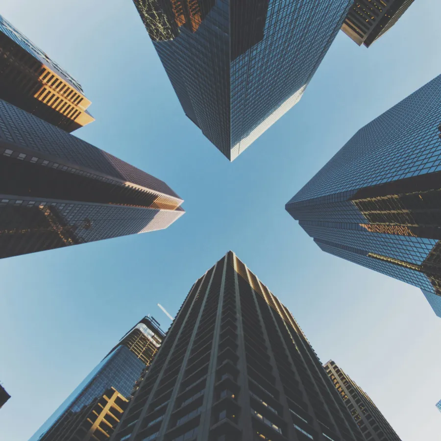 Upward view of tall modern skyscrapers against a clear blue sky in a city center.