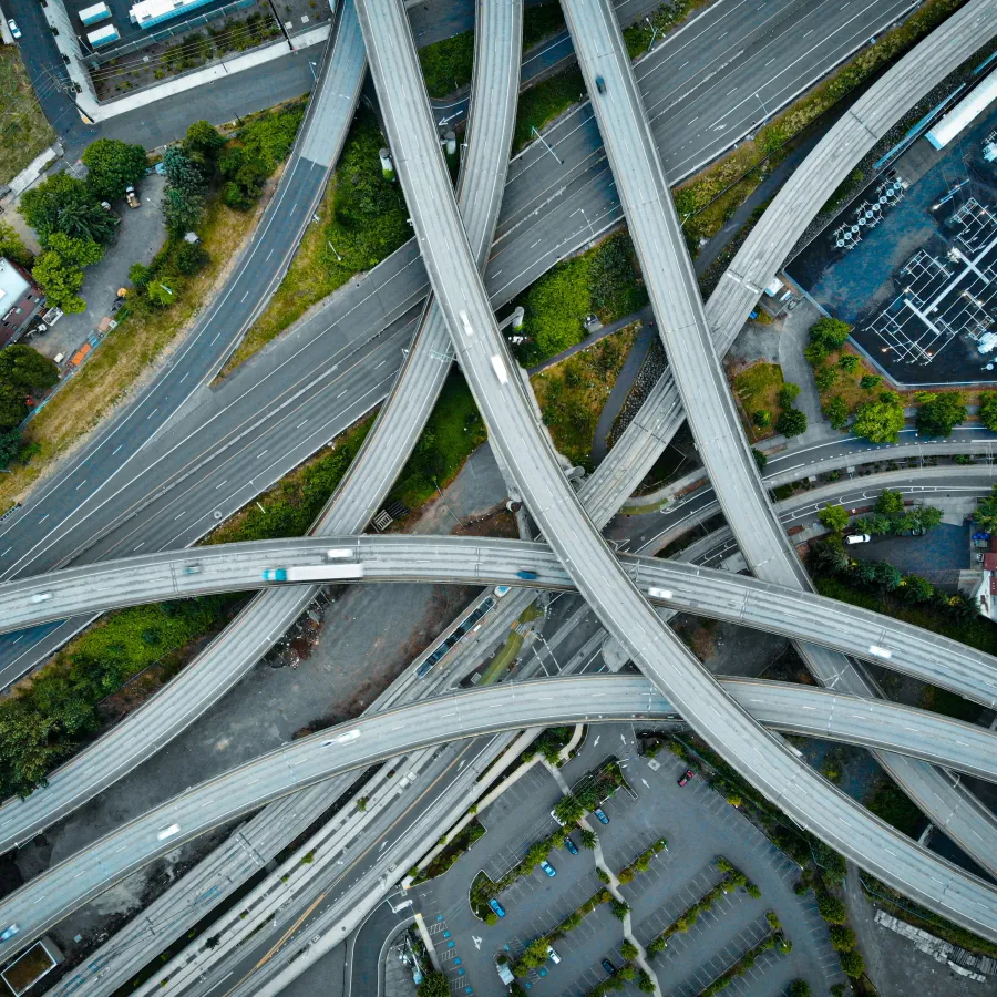 Aerial view of a busy multi-level highway interchange with vehicles and surrounding buildings.