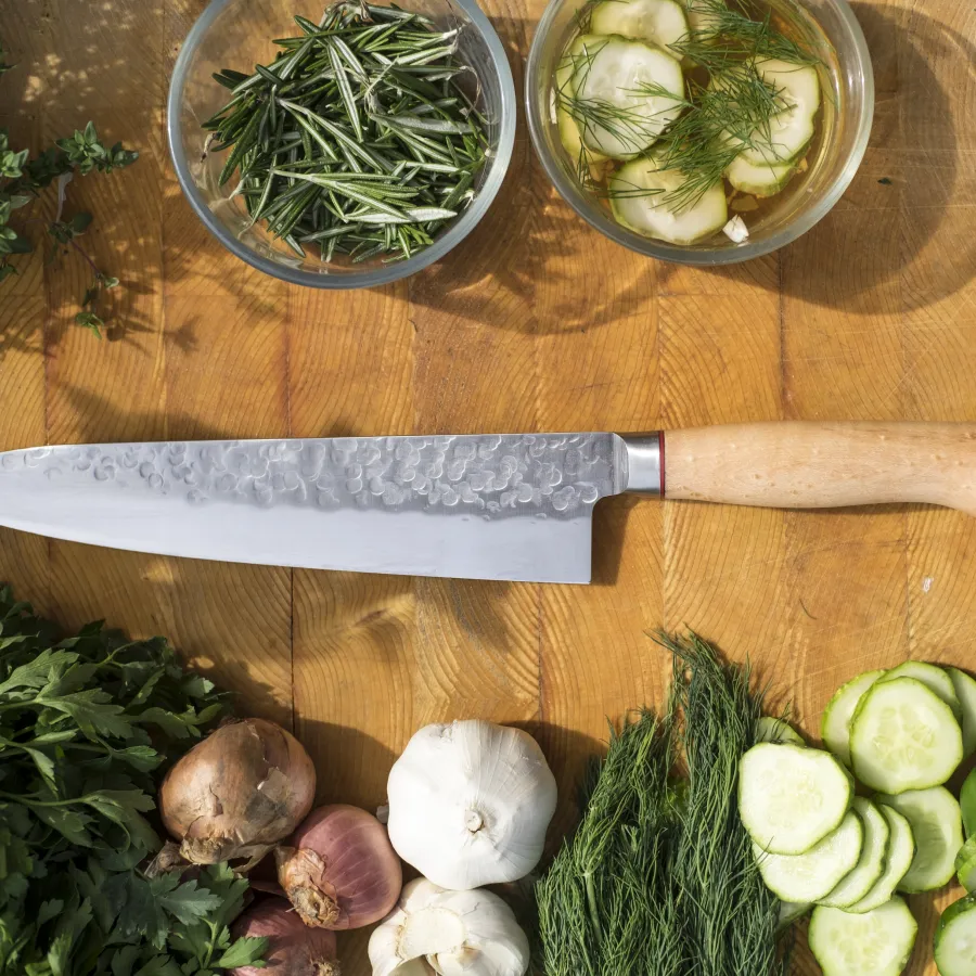 a knife next to a cutting board with vegetables on it