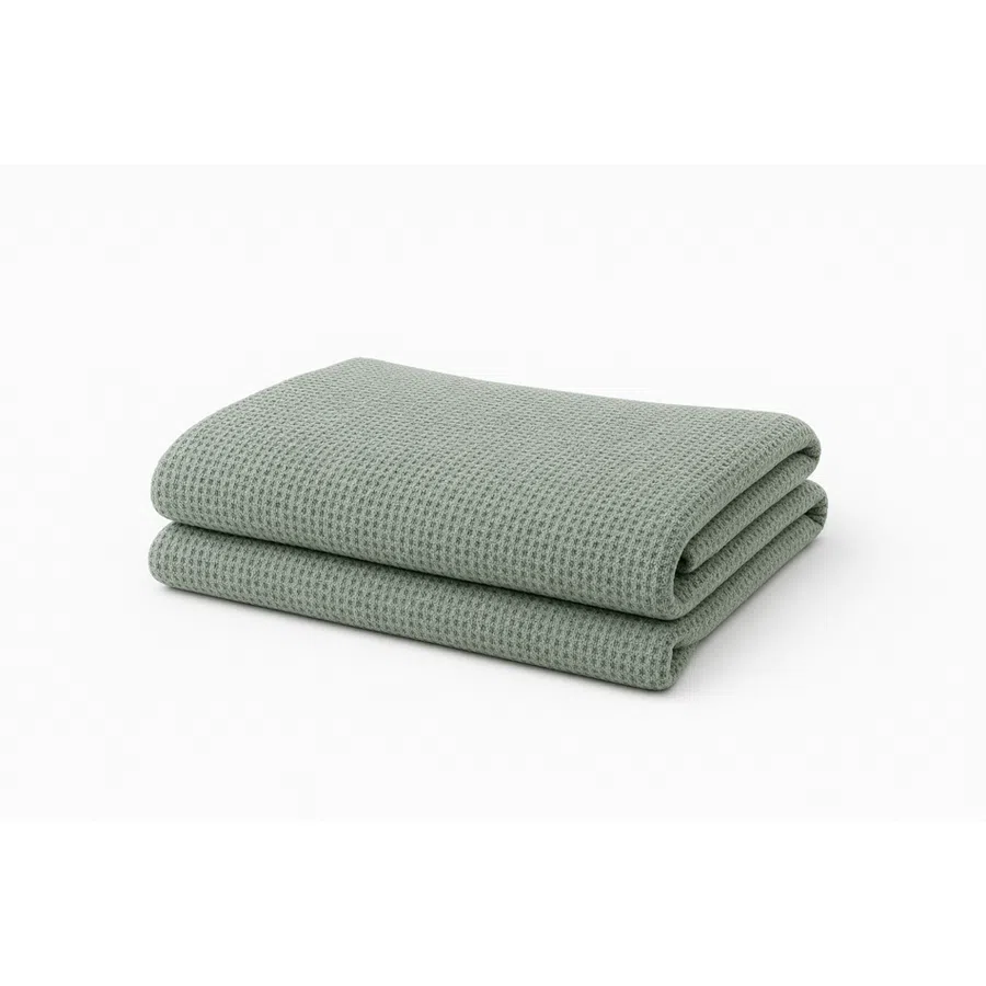 Folded light green waffle weave textured blanket on a white background