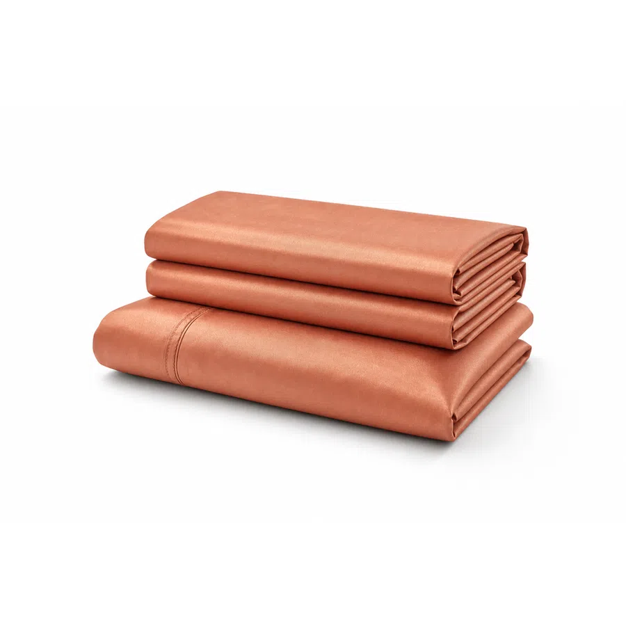 Stack of neatly folded terracotta colored bed sheets on a white background.
