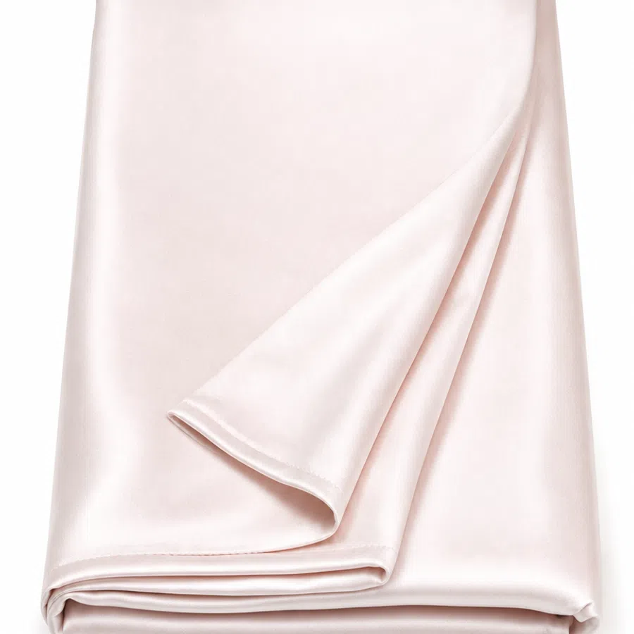 Folded pale pink satin fabric with smooth, shiny texture against a white background