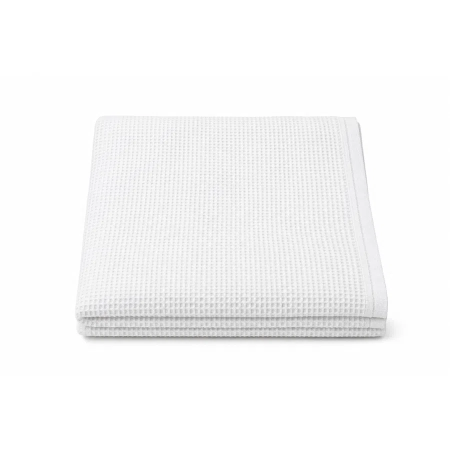 Folded white waffle weave textured towel on a white background