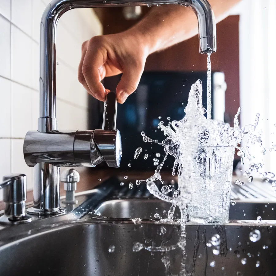 a hand pouring water into a faucet