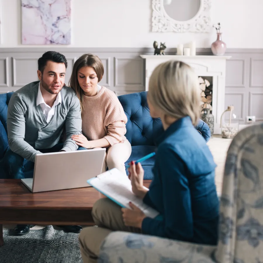 a group of people sitting on a couch looking at a laptop